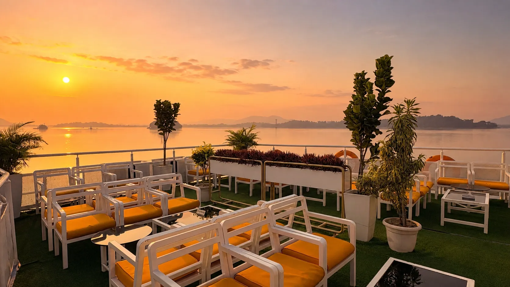 Upper deck of Alfresco Grand at golden hour — open seating, plants and the river all around