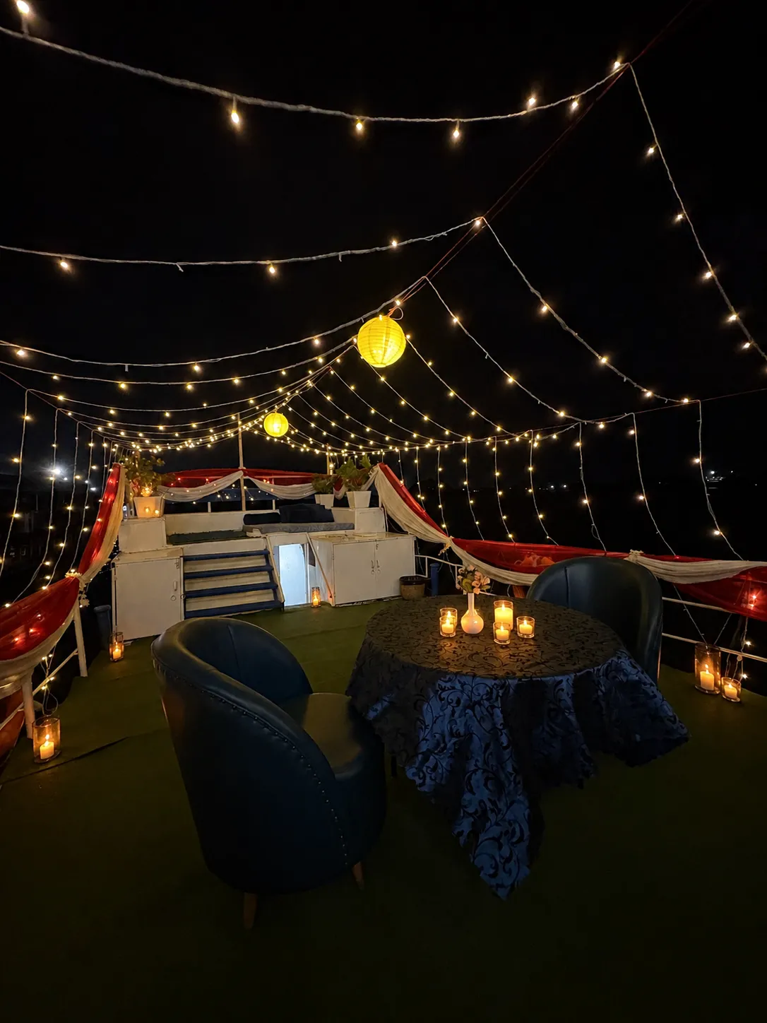 Candlelit table for two under a canopy of fairy lights on the deck of S B Agam