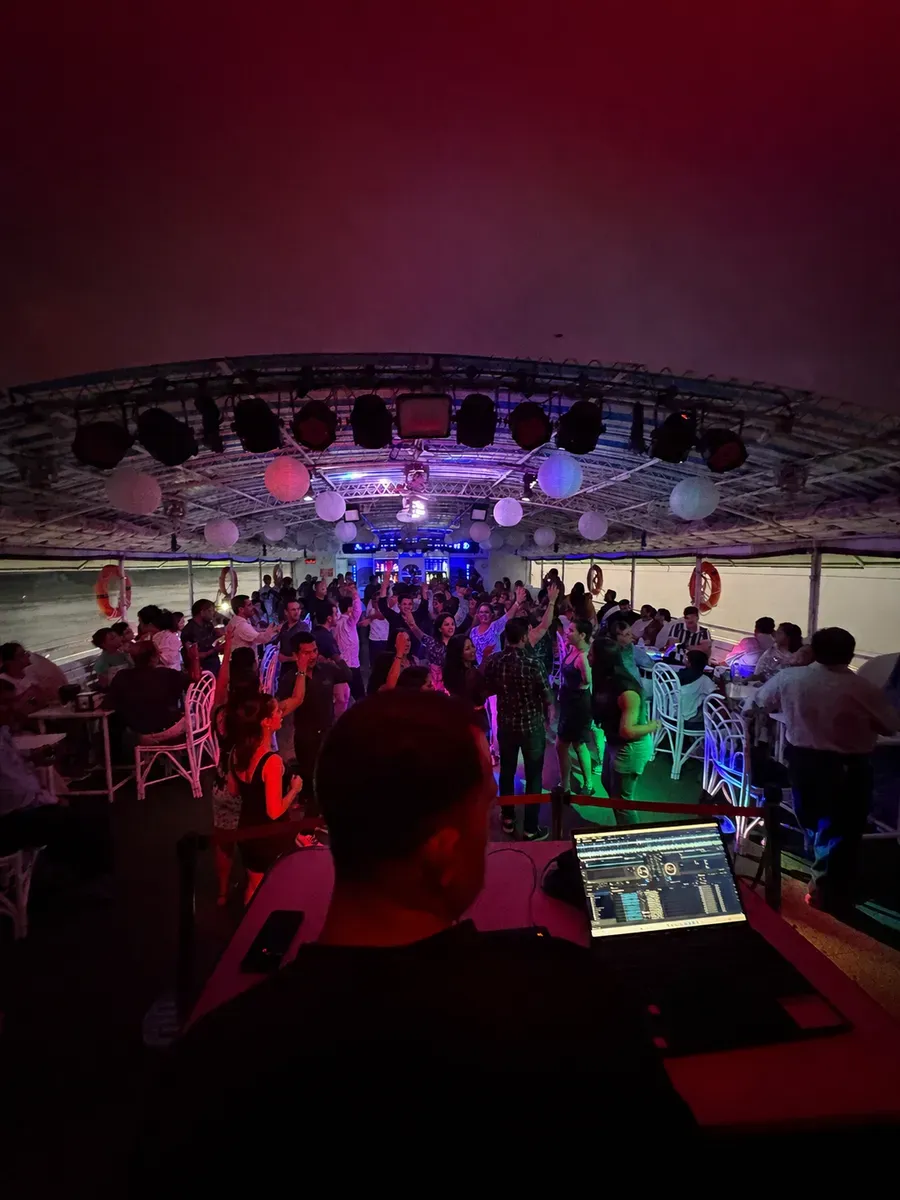 DJ playing to guests dancing on the covered middle deck of Alfresco Grand at night