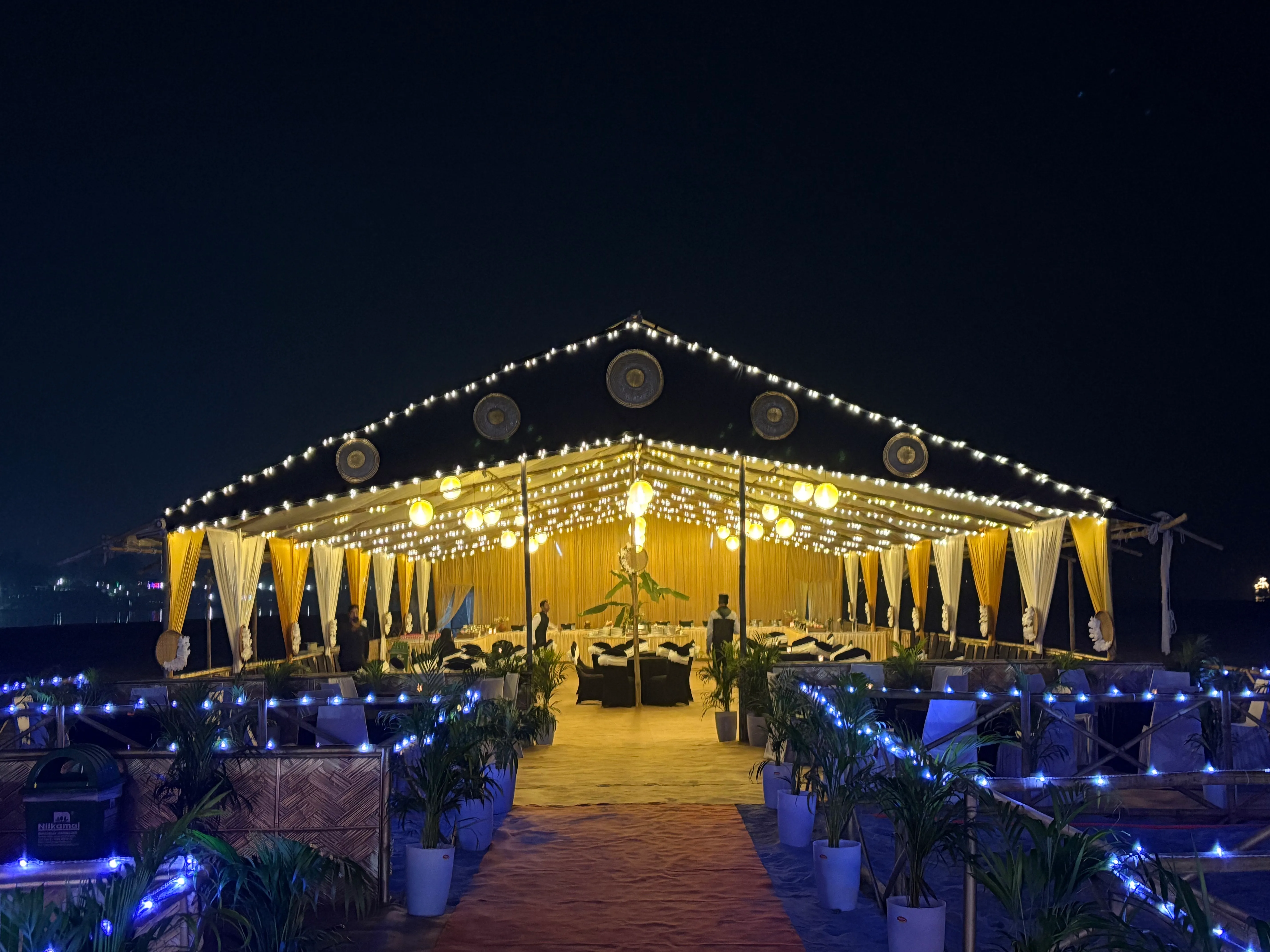 Lit wedding marquee glowing at night on the Brahmaputra river island