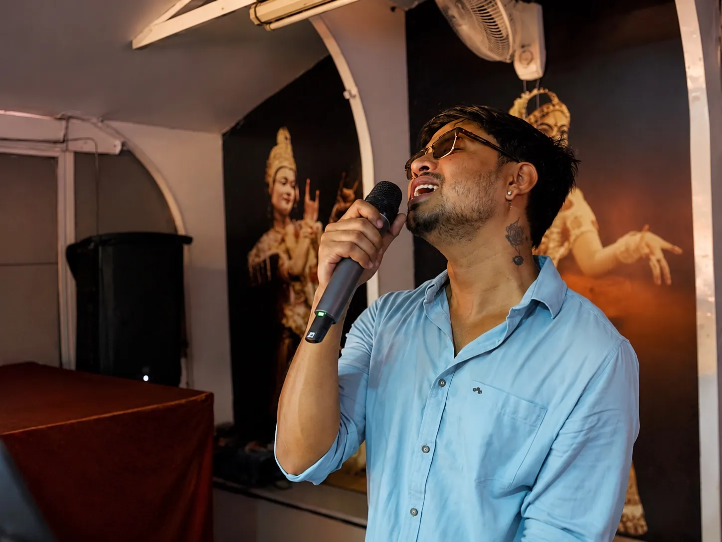 Live singer performing on the cruise deck with Sattriya dance murals behind the stage