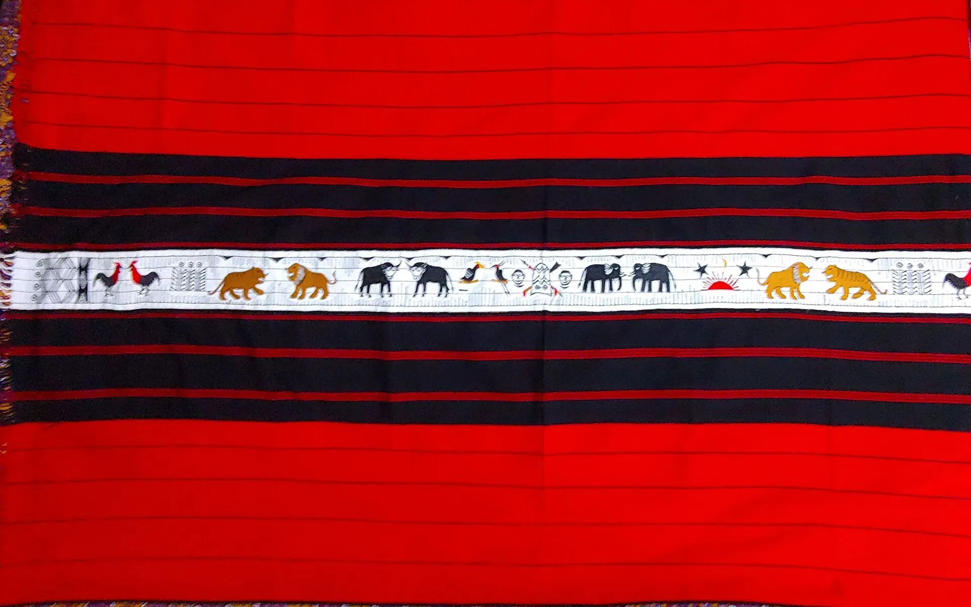 Handwoven Naga shawl in red with black bands and fine red pinstripes, its central white band carrying woven figures of mithun, elephants, tigers and roosters