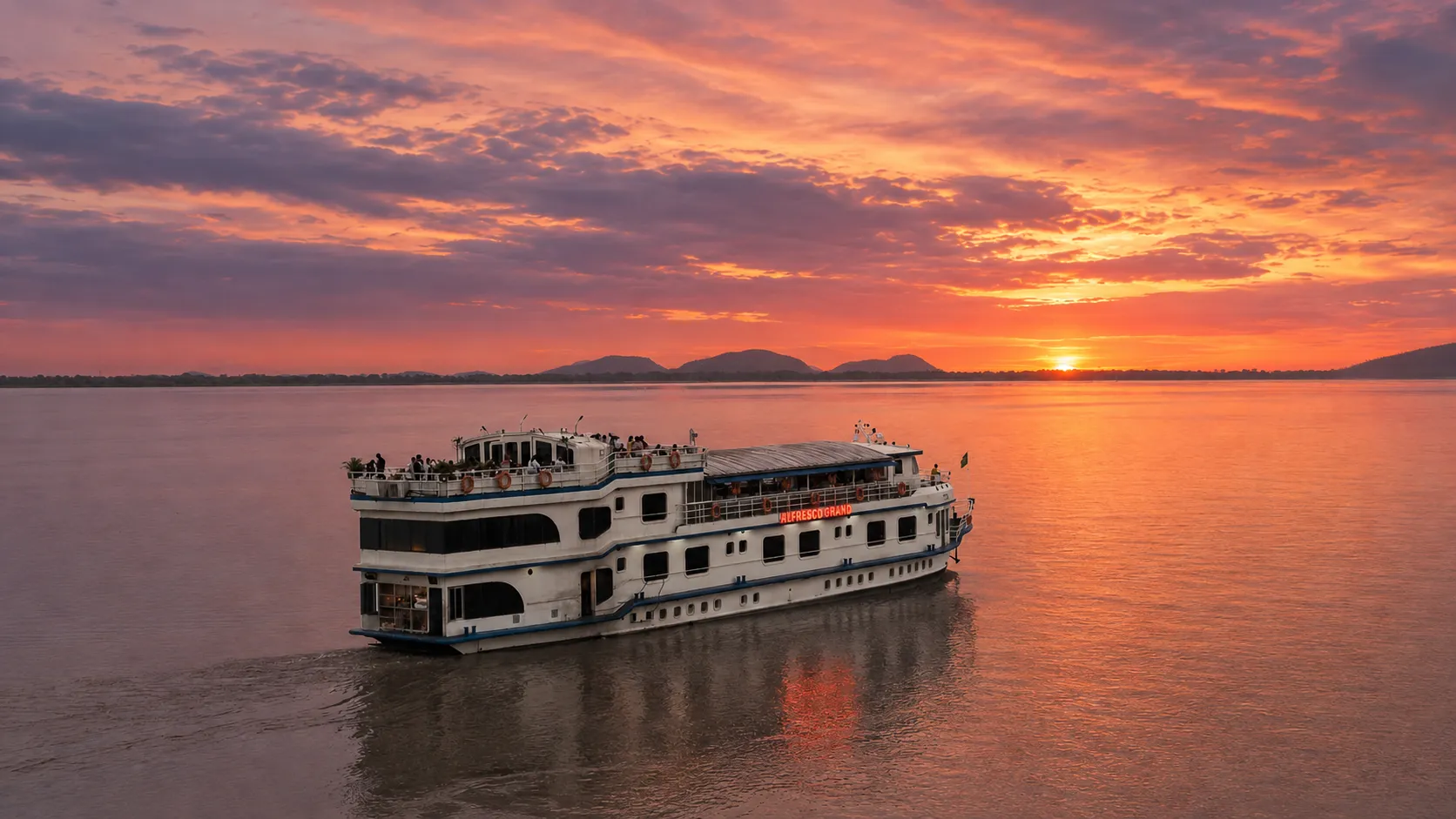 Alfresco Grand sailing the Brahmaputra under a blazing orange and pink sunset